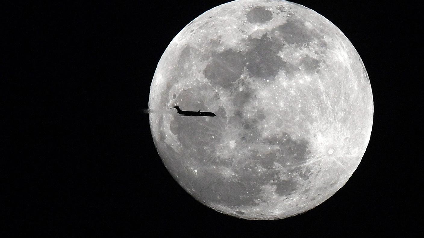 Un aereo passa davanti alla "superluna" piena, iniziata la scorsa notte