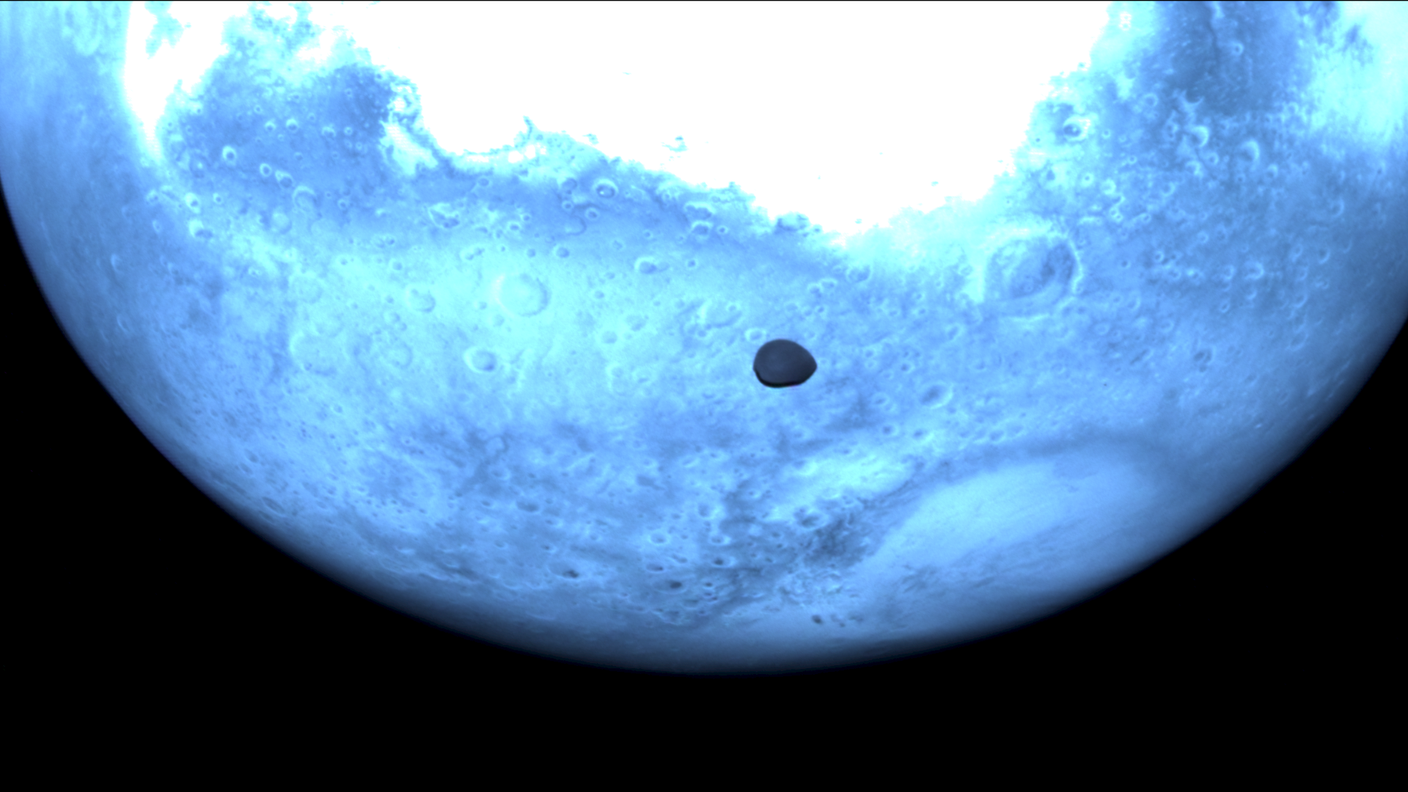 Deimos con Marte sullo sfondo fotografato dalla sonda della missione Hera