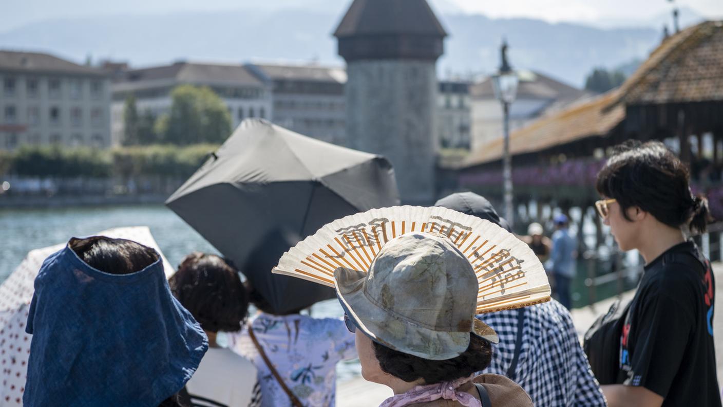 Turisti asiatici provano a difendersi dal caldo nei pressi del celebre Kapellbrücke