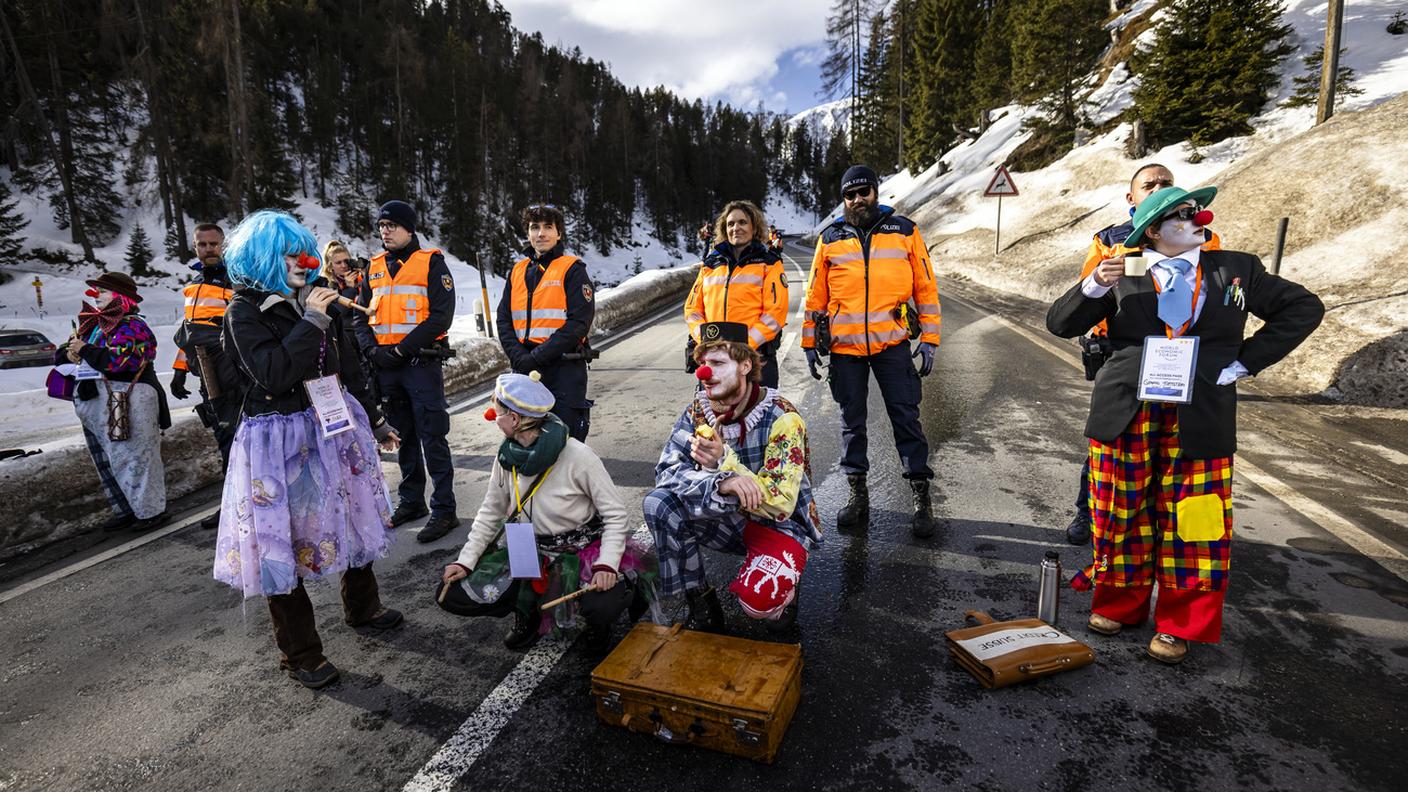 Dimostranti vestiti da clown e agenti sulla strada presso Davos