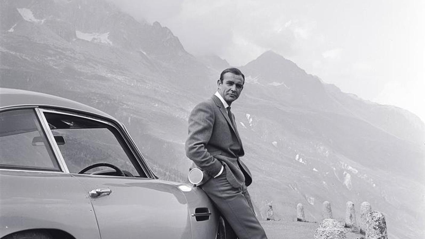 Sean Connery con l'Aston Martin DB5 nelle Alpi svizzere durante le riprese del film "Goldfinger" - 1964