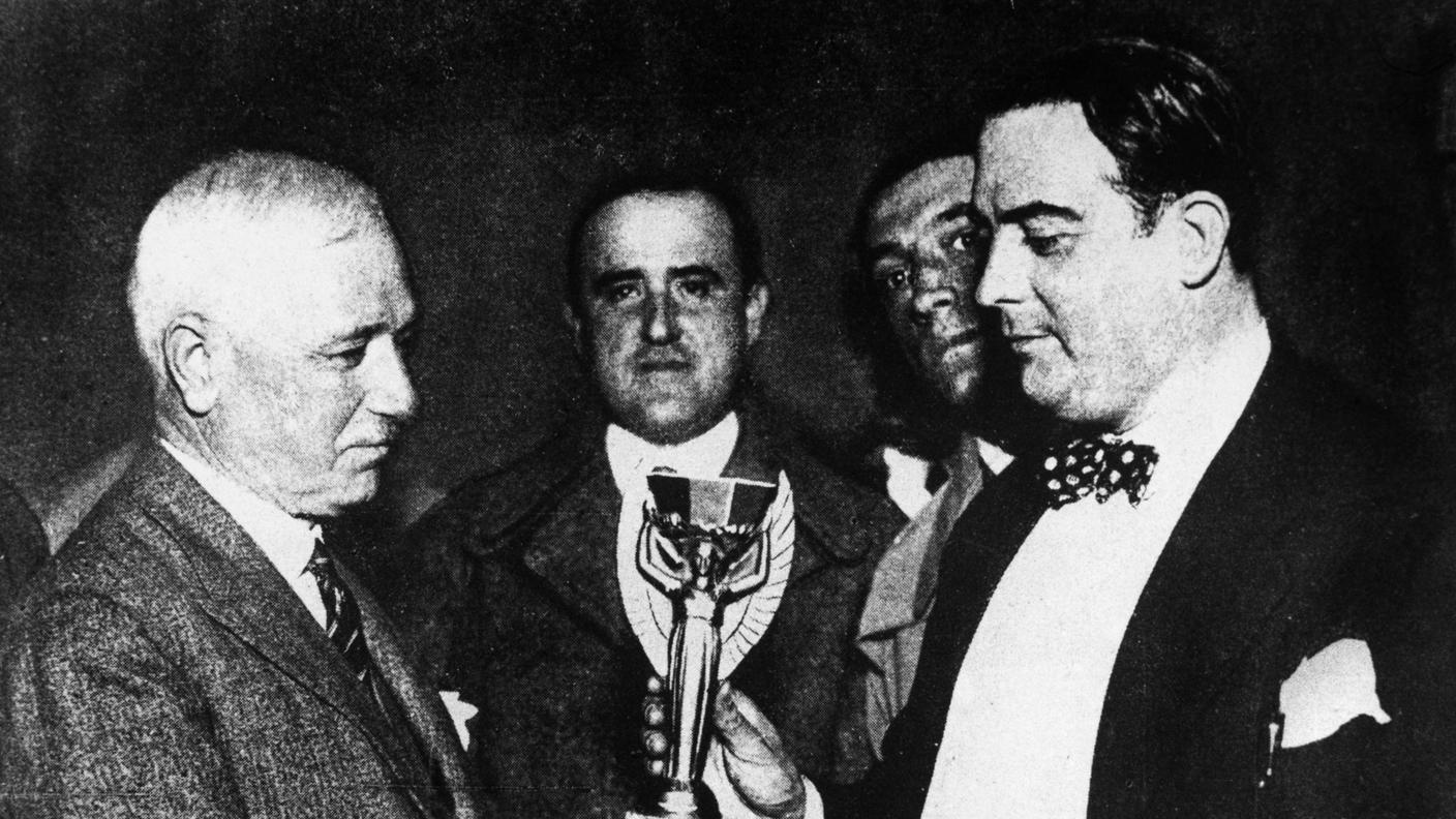 Coppa del Mondo: Trofeo, 1930 - Jules Rimet (a sinistra), presidente della FIFA (Federation Internationale de Football), consegna il primo trofeo della Coppa del Mondo al dott. Paul Jude, presidente dell’Associazione Calcistica Uruguaiana, dopo la vittoria dell’Uruguay sull’Argentina, 30 luglio 1930.